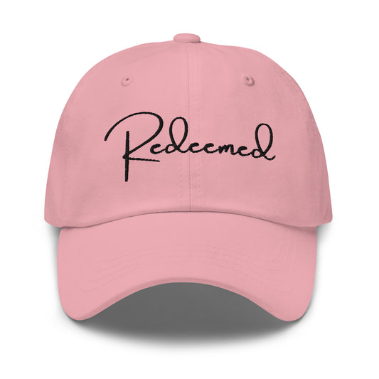 Front view of pink dad hat with 'Redeemed' embroidered in black script