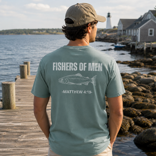 Man standing on a coastal dock wearing the Fishers of Men Tee in Green Bay featuring a fish graphic and Matthew 4:19 on the back.