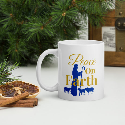 Peace on Earth Christmas mug with shepherd and sheep design, left handle view in front of Christmas tree
