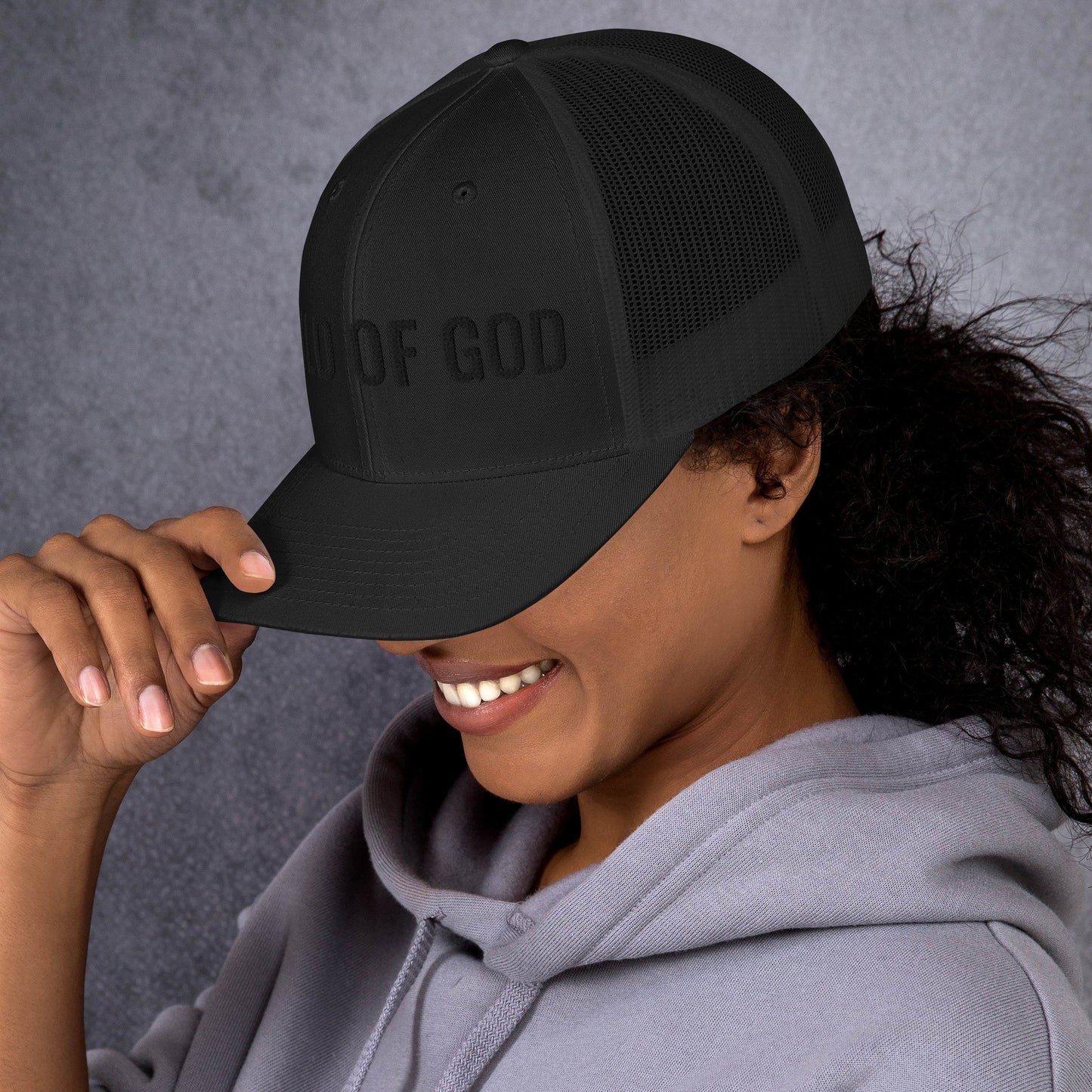 Woman styling minimalist Child of God black trucker hat casual faith based outfit