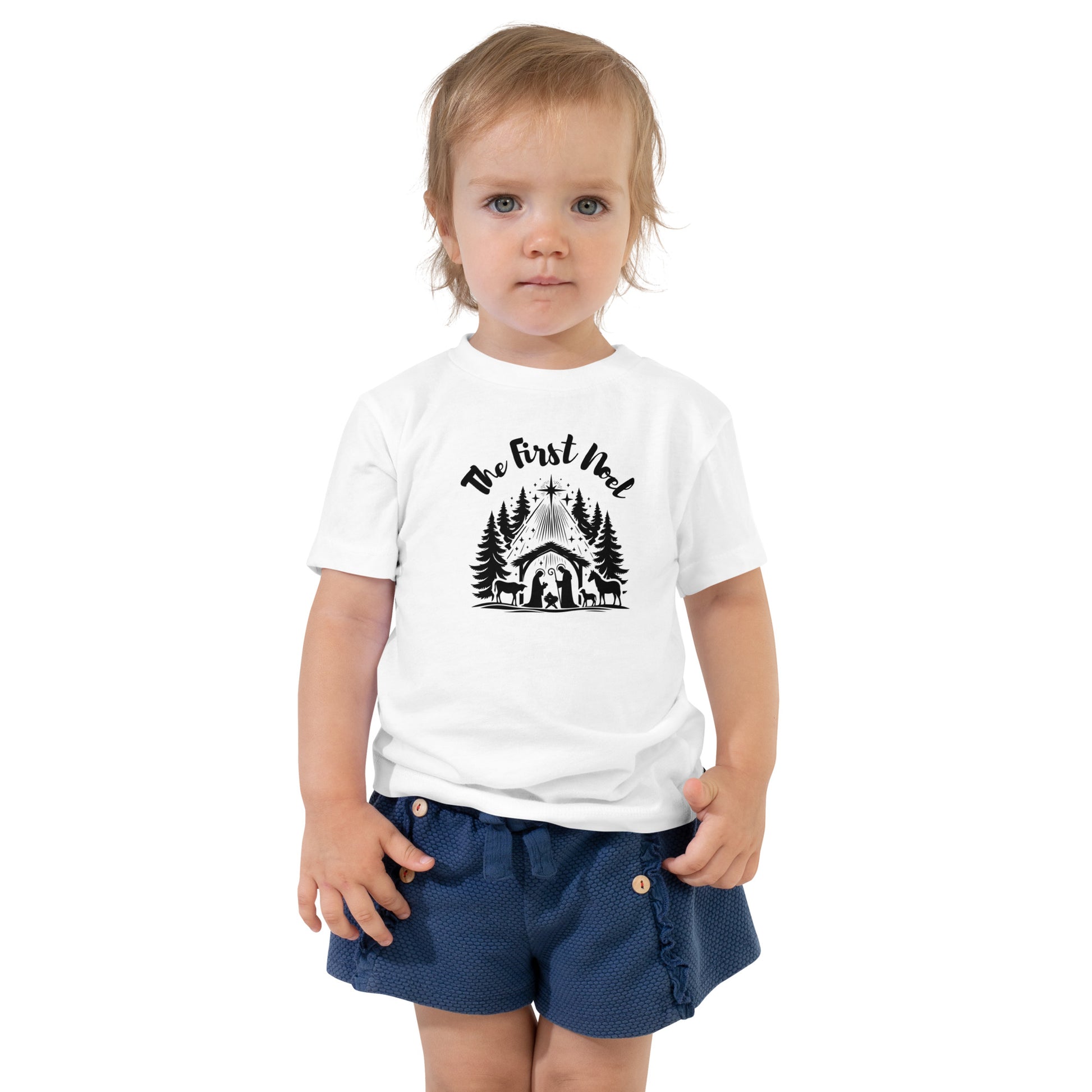 Toddler white Christian Christmas tee with black nativity design and The First Noel text inspired by Luke 2:11.
