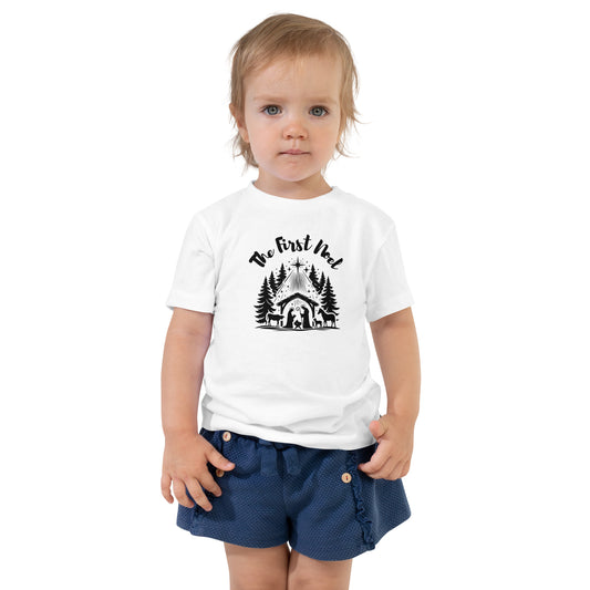Toddler white Christian Christmas tee with black nativity design and The First Noel text inspired by Luke 2:11.

