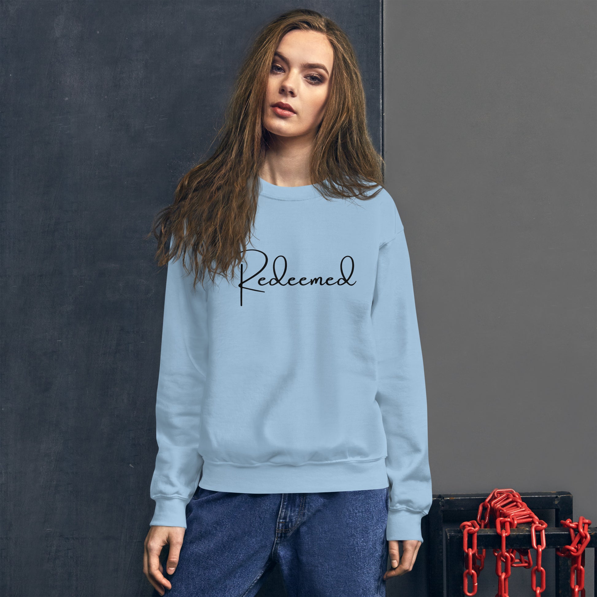 Woman in Light Blue Redeemed crewneck sweatshirt, relaxed lifestyle pose, front view.