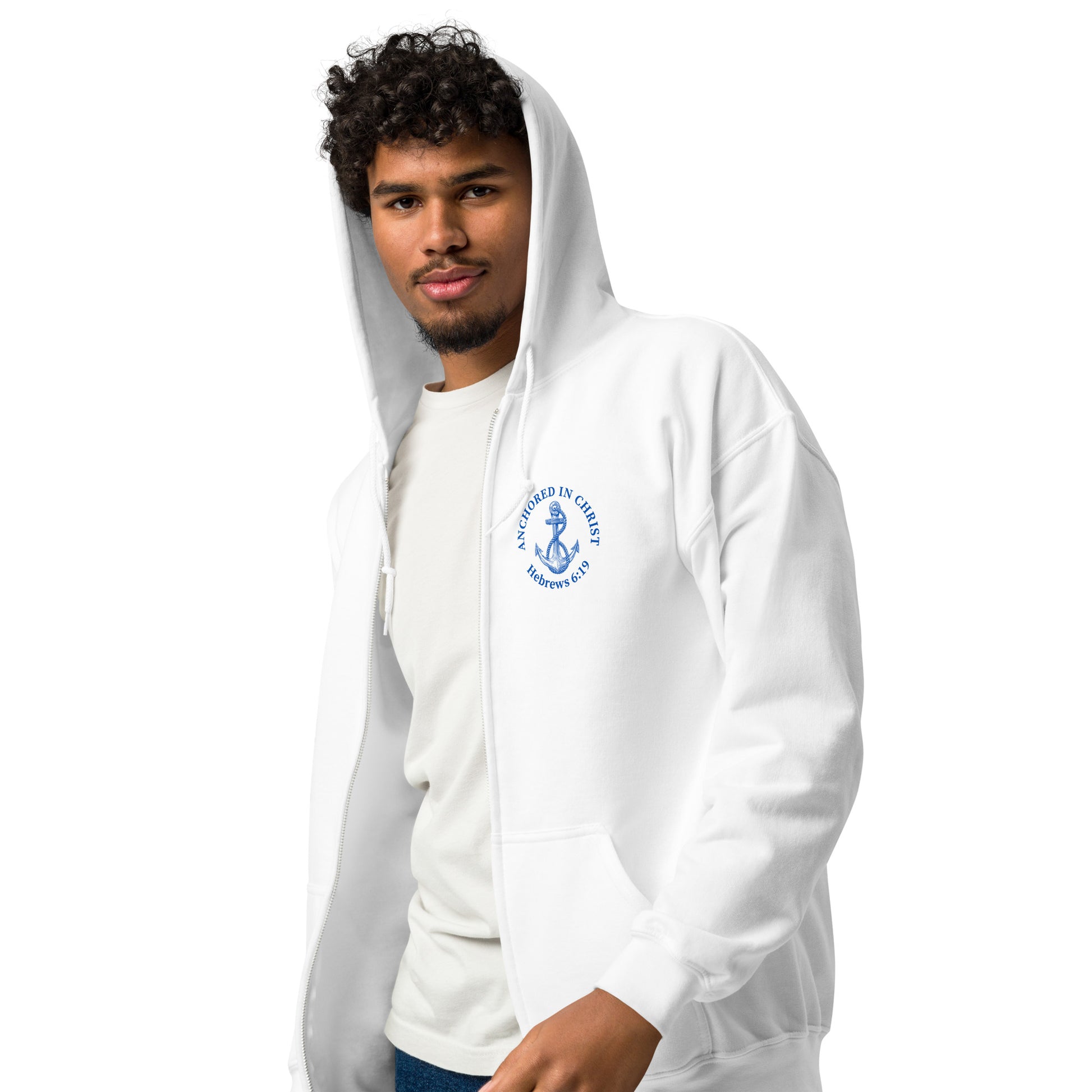 Young man wearing the white full zip hoodie with the hood up, shown from an angled front view highlighting the left chest design with "Anchored in Christ – Hebrews 6:19."