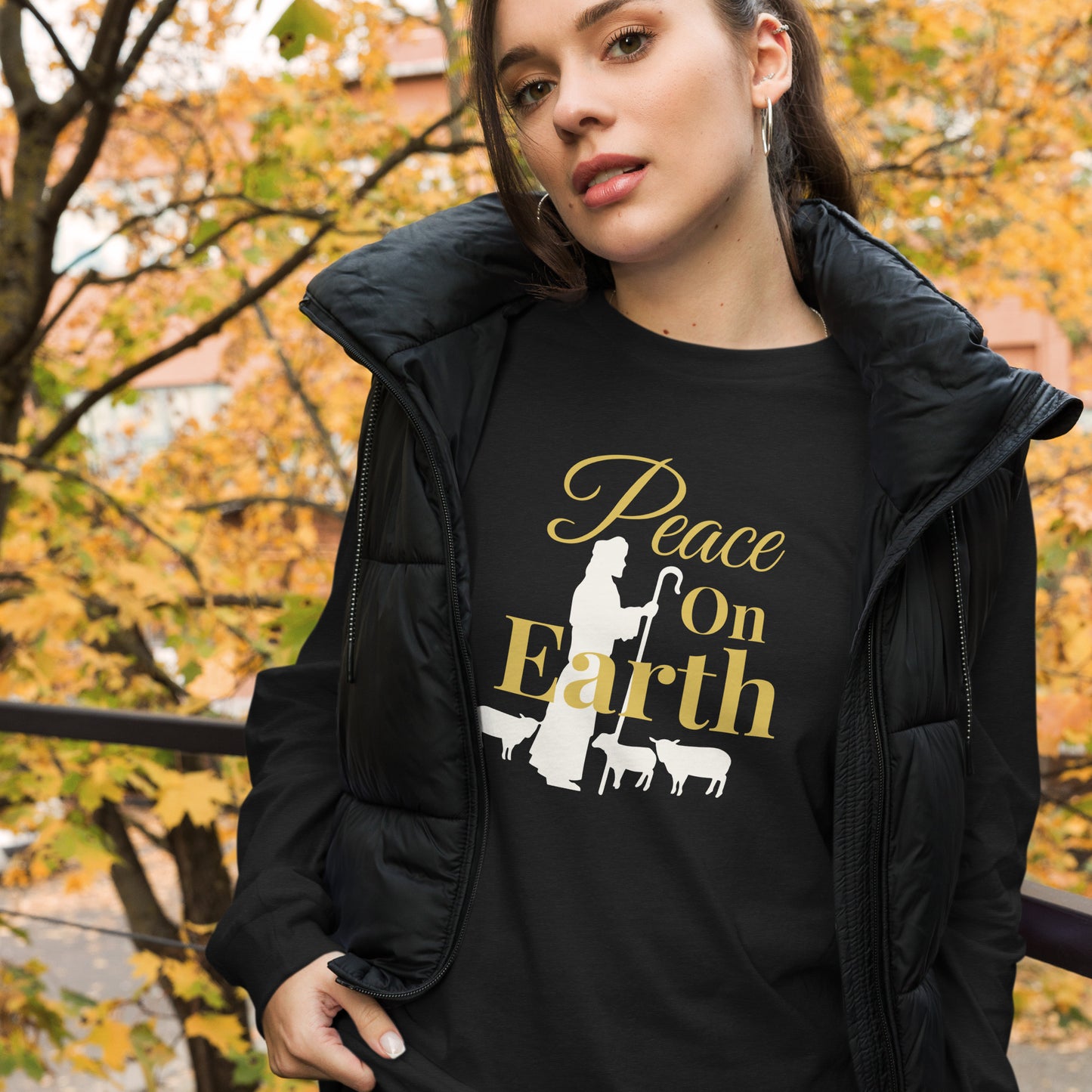 Woman wearing Peace on Earth long sleeve Christmas shirt with shepherd and sheep design, styled with vest on fall day

