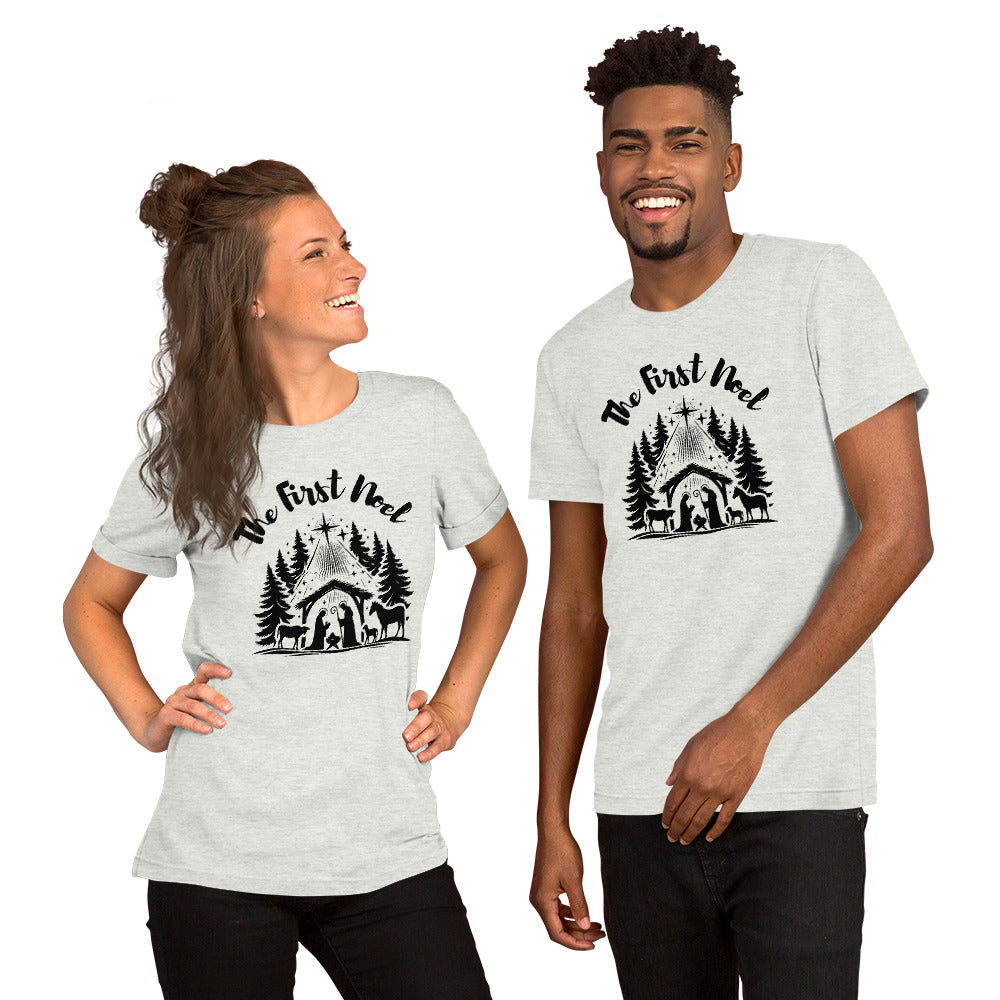 Couple wearing matching Ash Gray First Noel shirts with black text and nativity graphic featuring the manger, pine trees, and Christmas star.
