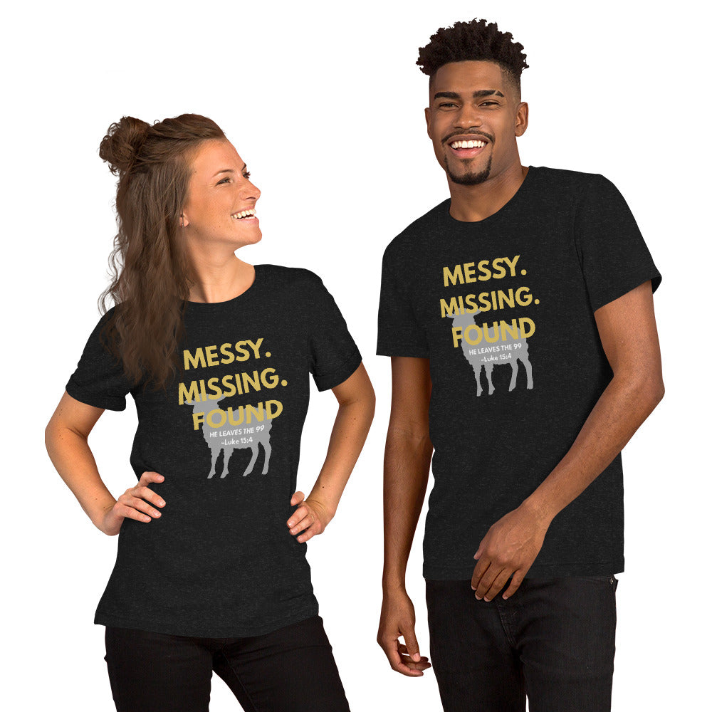 Happy couple wearing matching black heather “Messy. Missing. Found.” Christian t-shirts, standing together and smiling, front design with lamb silhouette and Luke 15:4 visible
